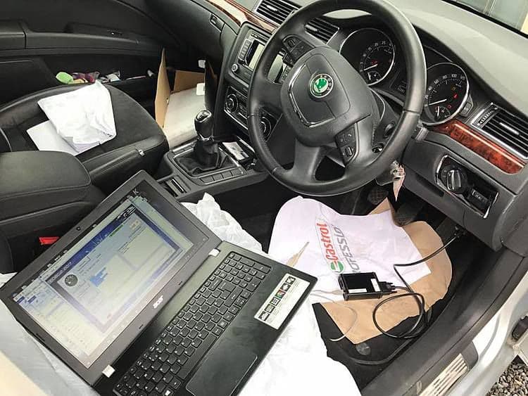 OBD tuning laptop connected in a vehicle cabin during calibration